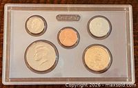 Front view of sealed lens showing obverse of five proof coins