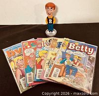 Front view of six bagged Archie comics and Archie bobblehead