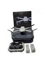 Drone unfolded on case with controller, batteries, box visible