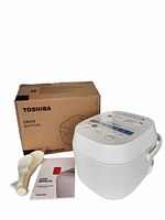 Rice cooker with box, paddle and manual in view