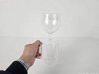 Hand holding reversible glass showing both mug and goblet sections with etching visible