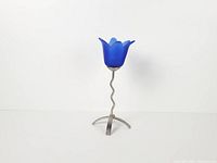 Full view showing candlestick holder with blue glass tulip cup and wavy metal stem