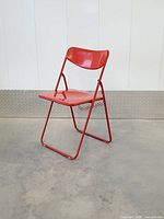 Three-quarter left view of red folding chair fully opened