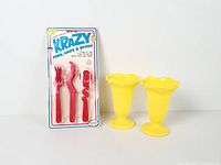 Packaged Krazy utensil set alongside two yellow sundae cups