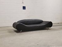 Front view of black curved semi-leather sofa with metal legs