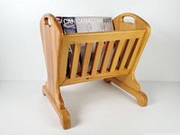 Three-quarter view showing cradle form, slatted sides, carry handle, and scale