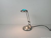 Full view of silver telescopic desk lamp illuminated