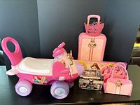 Group shot showing ride-on toy, suitcase, handbags, vanity case, crown topper