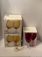 Two boxes of amber gold goblets and one box of red goblets displayed together