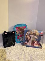 Group shot of black cat plush purse, blue LOL backpack, boxed NYE Queen doll