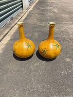 Pair of matching tall yellow-orange ceramic vases on pavement