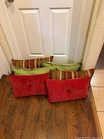 Six decorative throw pillows arranged against door showing red velvet, green, and striped designs