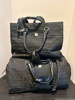 Front view of both DVF black cloth travel bags stacked