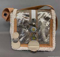 Front view showing metallic perforated satin panel, wool sides, leather trim, jeweled embellishment