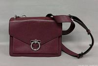 Front view of burgundy Rebecca Minkoff crossbody bag showing flap and ring hardware