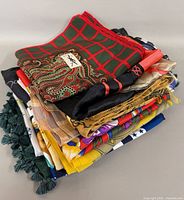 Stack of approximately twelve assorted scarves showing various patterns and colours
