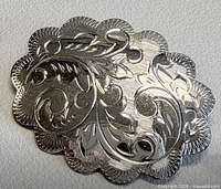 Front view showing scalloped oval shape and floral engraving