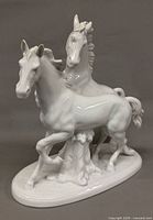 Front view of glossy white porcelain two-horse figurine on oval base
