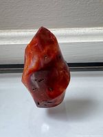 Front view of orange-red polished carnelian tower showing pointed tip and pits