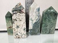 Front view of four moss agate towers beside ruler