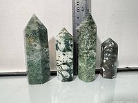 Front view of four moss agate towers beside ruler
