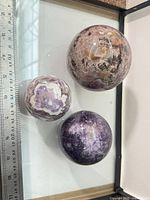Three polished mineral spheres next to ruler showing scale