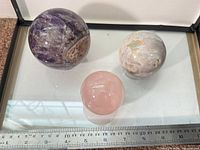 Group view of three crystal spheres on glass with ruler for scale