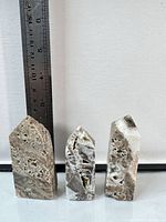 Front view of three polished quartz and sphalerite towers beside ruler showing ~3 in height