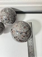 Three spheres beside ruler showing ~9–10 cm diameter and surface pattern