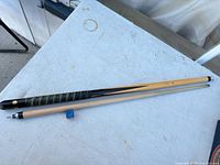 Two-piece snooker cue laid out with blue chalk cube