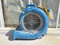 Front view of blue air blower fan showing intake grill, handle, and cord