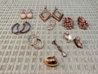 Group shot of all earrings and rings displayed on green textured background