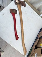 Two wood-handled axes on table