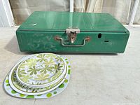 Front view of closed Coleman stove with stack of four patterned plates