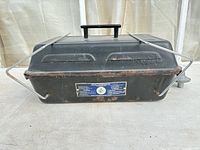 Closed black metal Keanall camp stove with handle and lid vents