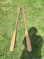 Full view of both wooden oars laid on grass