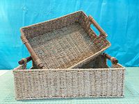 Two stacked rectangular woven baskets with wooden handles