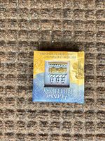 Front of mini booklet showing title and metal charm pins