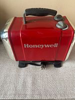 Front view showing Honeywell branding, red body, black base, power cord