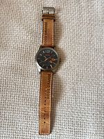 Full view of wristwatch laid flat showing dial, case, and entire strap