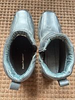 Top view of both boots showing interior lining, brand insole in left boot, missing right insole