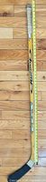 Full length view of yellow TPS Response hockey stick with tape measure for scale