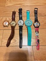 Five watches laid out showing fronts and straps