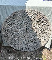 Front view of carved round wood panel showing floral relief