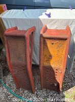 Pair of red perforated steel car ramps, rust visible
