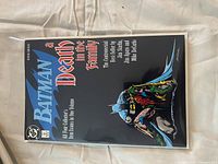 Front cover of collected edition showing Batman holding Robin, black background