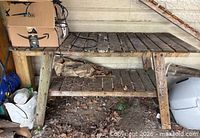 Overall view of wooden work table showing slatted top, lower shelf, A-frame legs