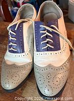 Front view of two-tone spectator flats showing brogue perforations and lace fronts