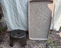 Black plastic step stool next to beige decorative plastic boot tray