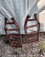 Pair of rusted cast iron ladder-style traction grips leaning against wall